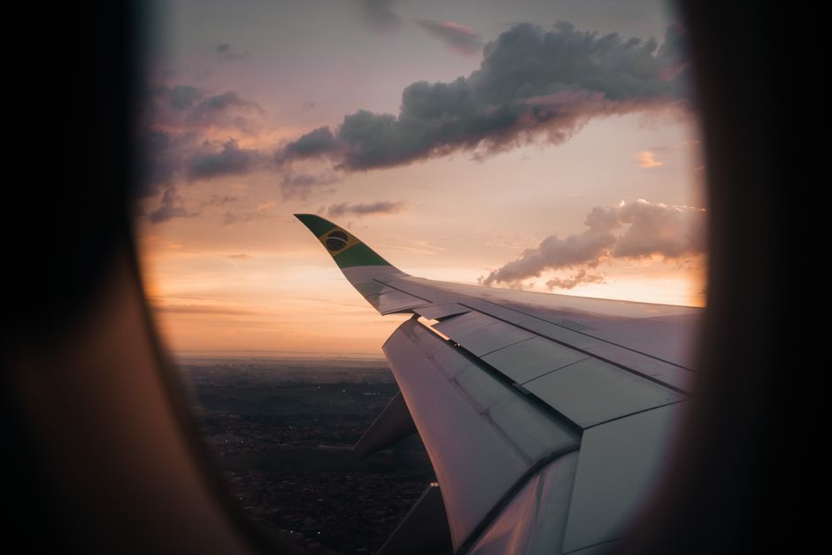 View from airplane window showing wing against a Brazilian sunset sky.